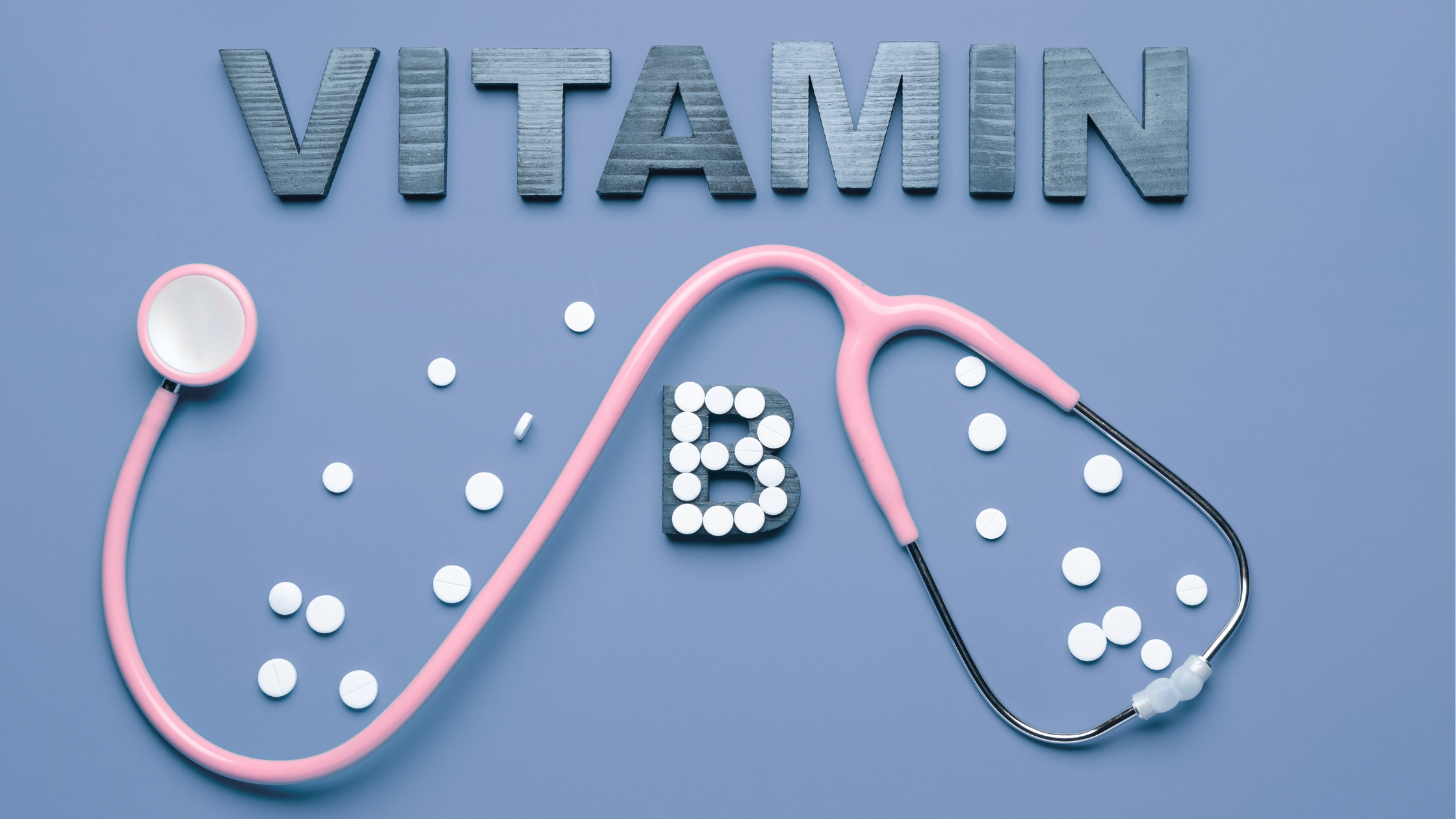 Wooden letters spelling vitamin with pills forming the letter B and a pink stethoscop