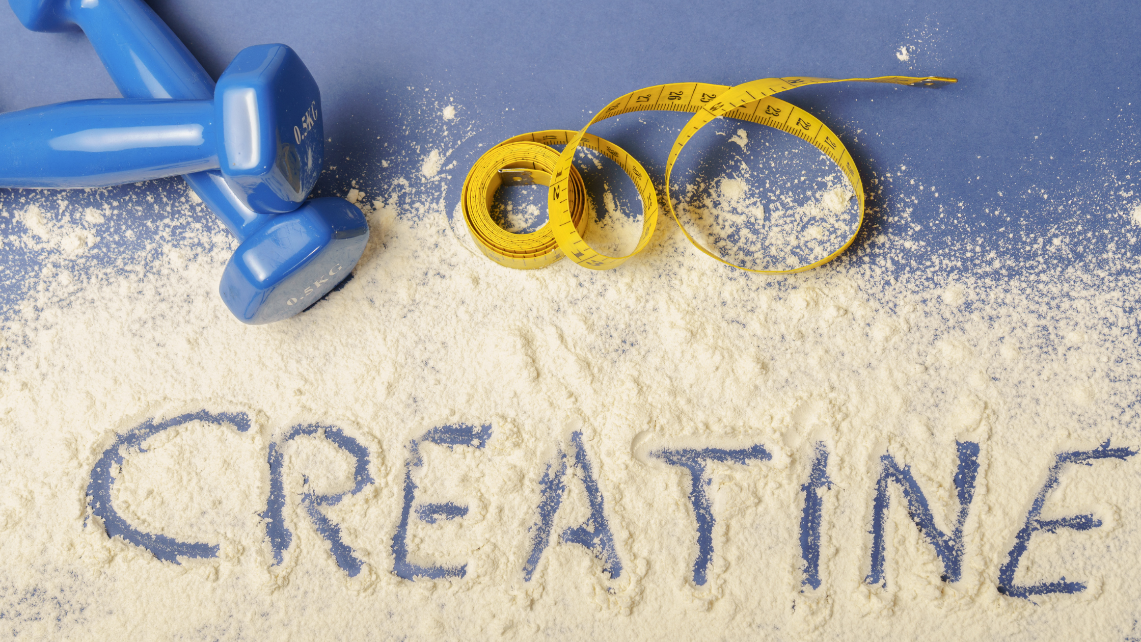 Blue dumbbells and yellow tape measure on creatine powder