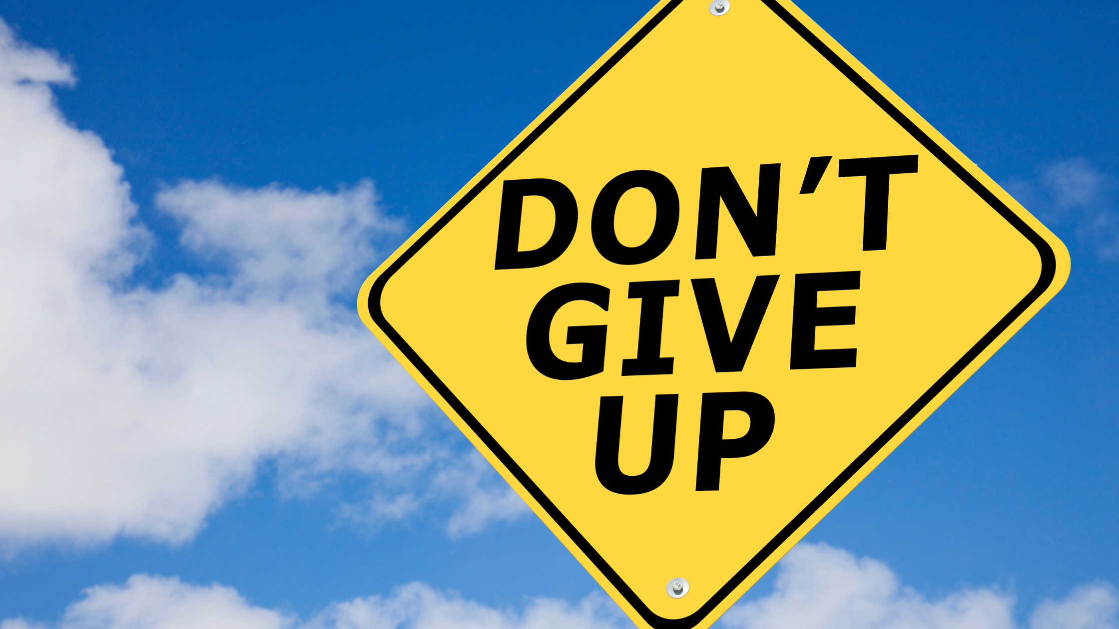 Yellow diamond sign with text 'DON'T GIVE UP' against blue sky