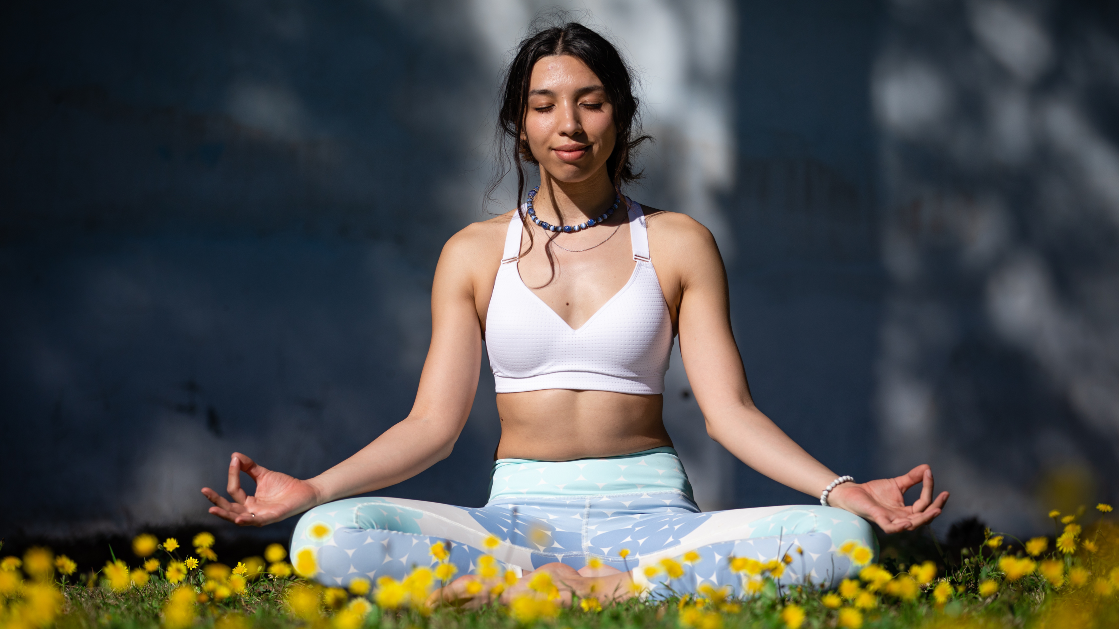 Woman meditating outdoors among yellow flowers