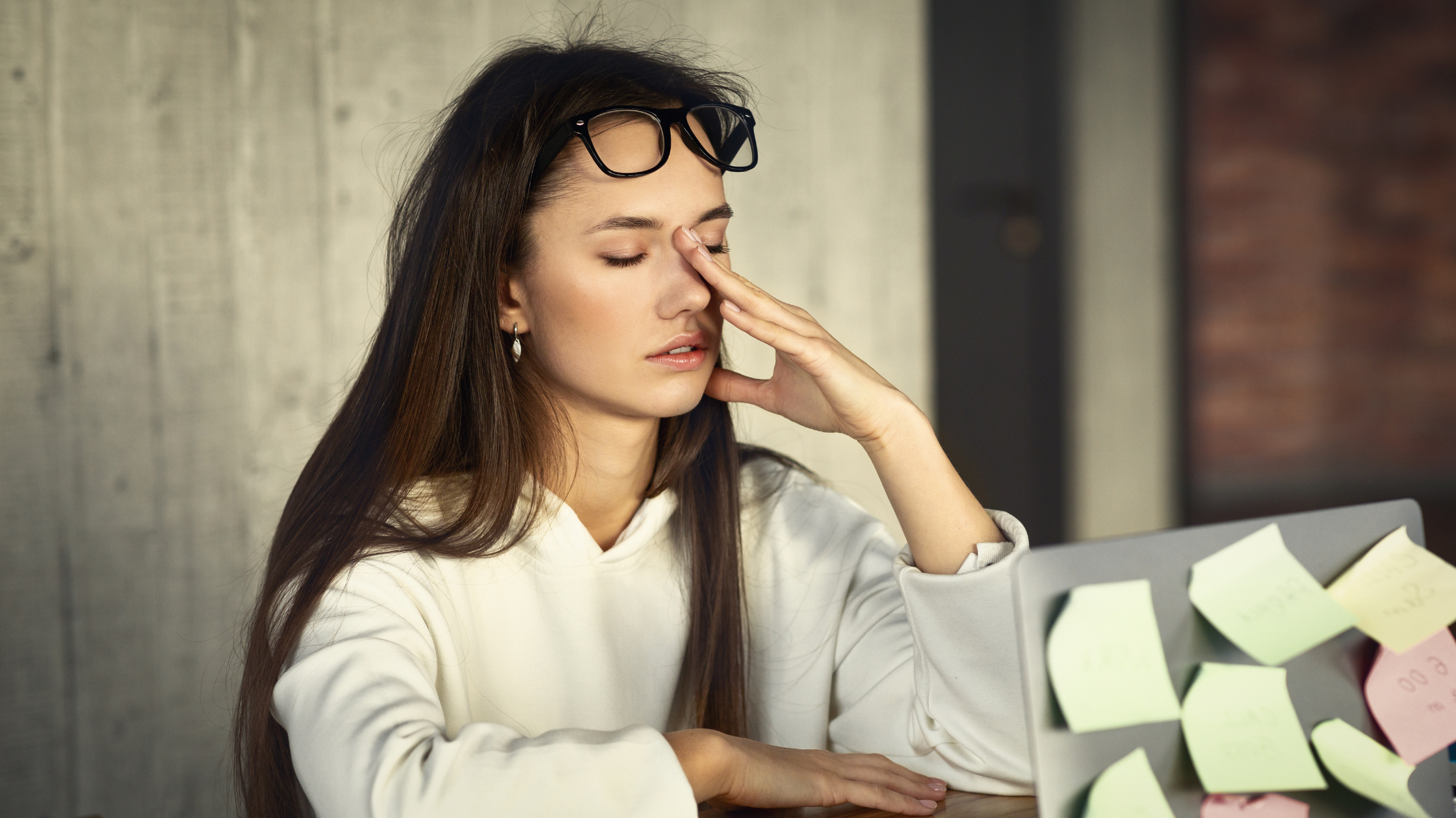 Tired woman rubbing her eyes at a desk