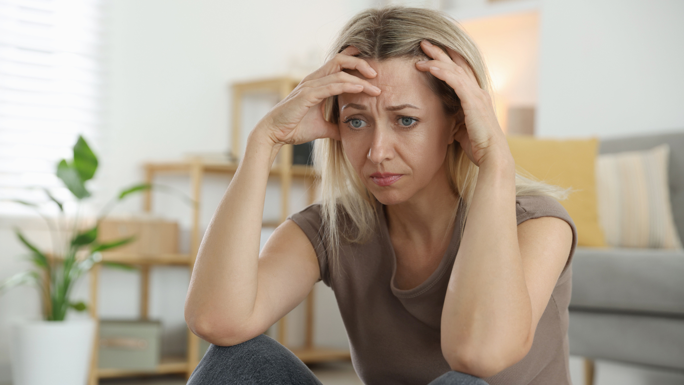 Worried woman holding her head indoors