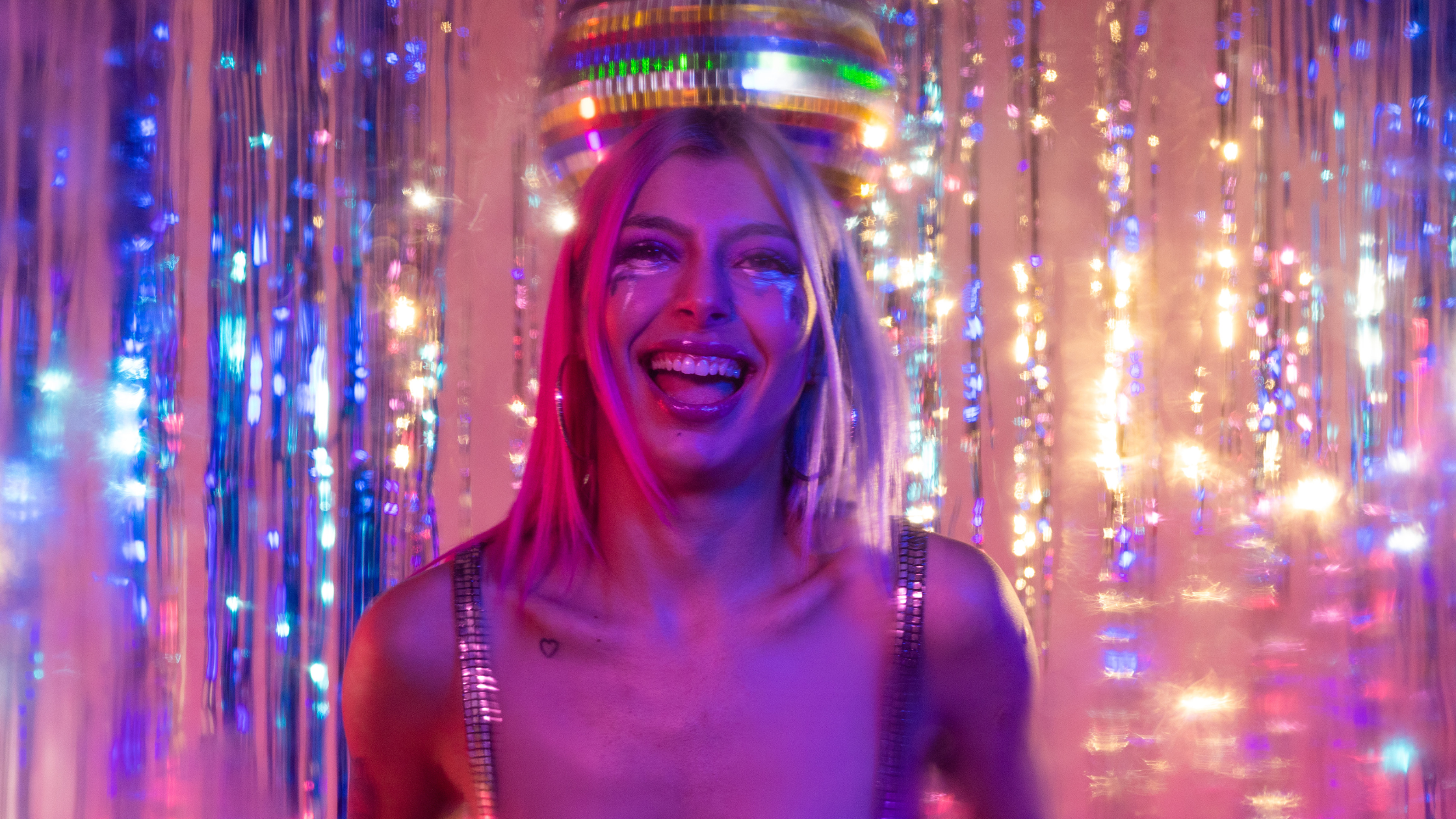 Person smiling brightly with colorful party lights in background