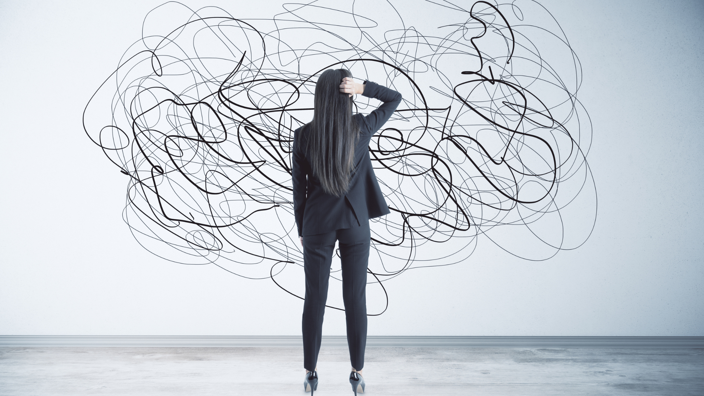Woman facing wall with chaotic black scribbles representing overthinking