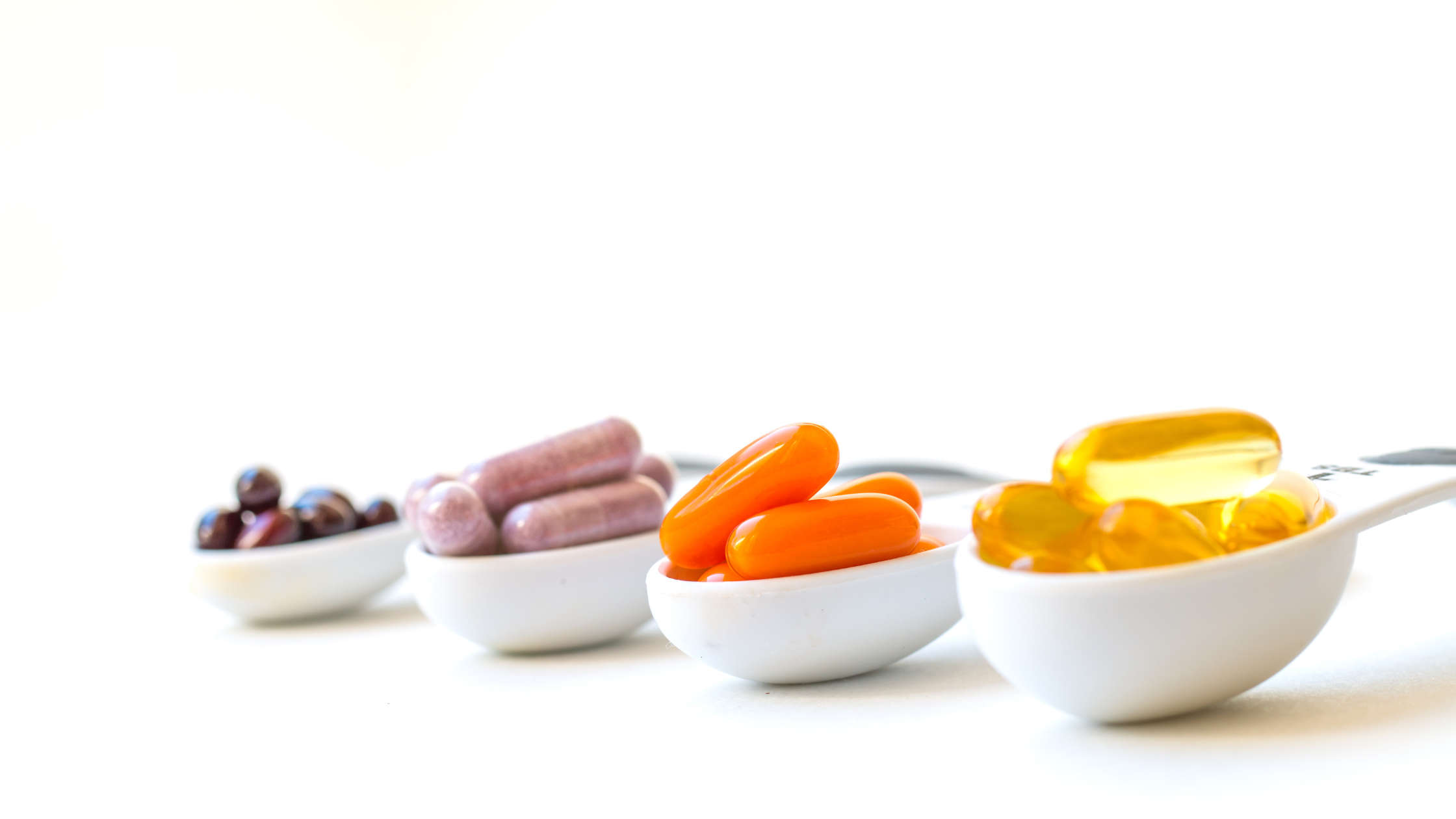 Various colored capsules and pills in white measuring spoons