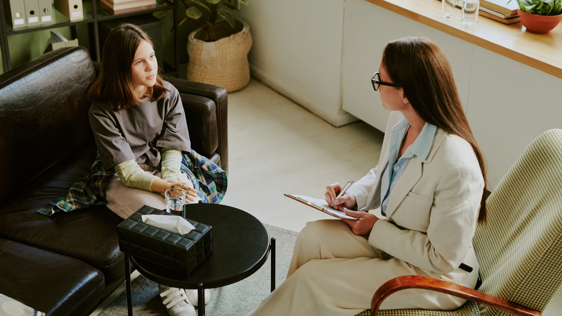 Therapist taking notes while patient talks on couch