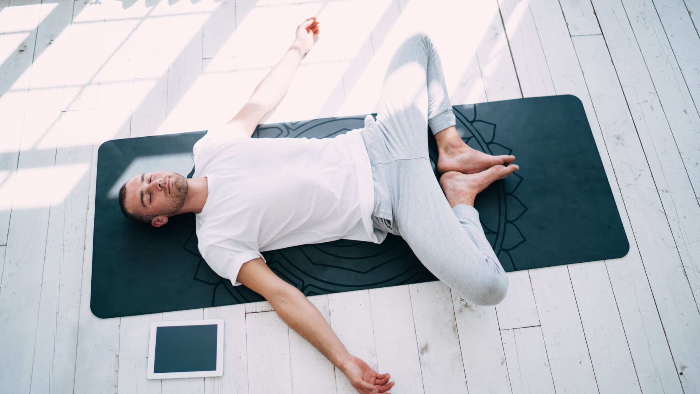 Man lying on yoga mat in a reclining twist pose