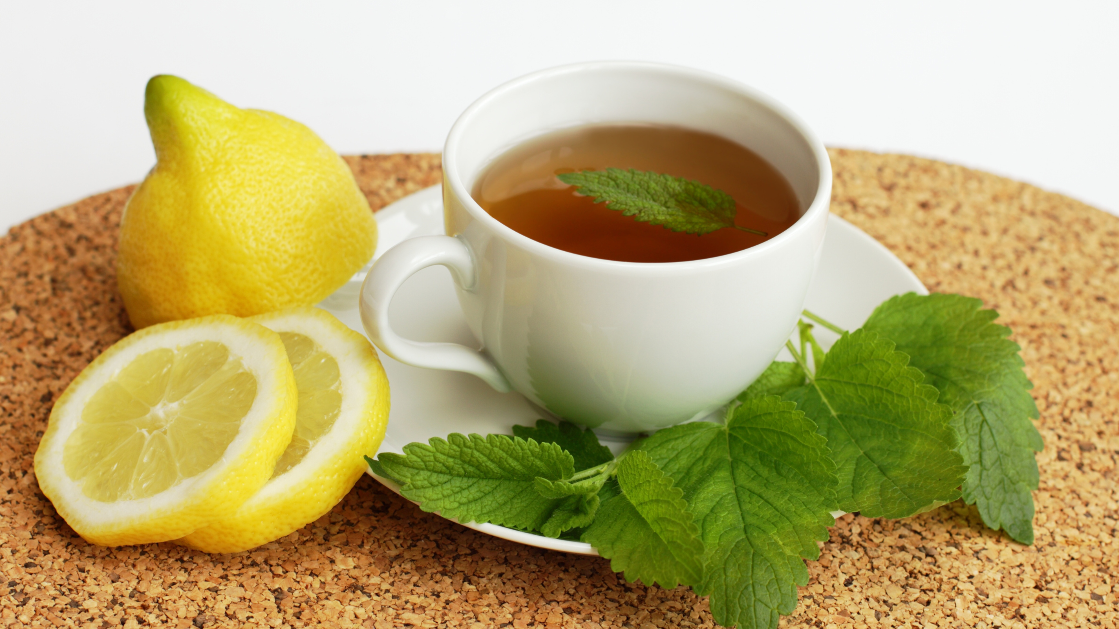 Cup of herbal tea with lemon slices and green leaves