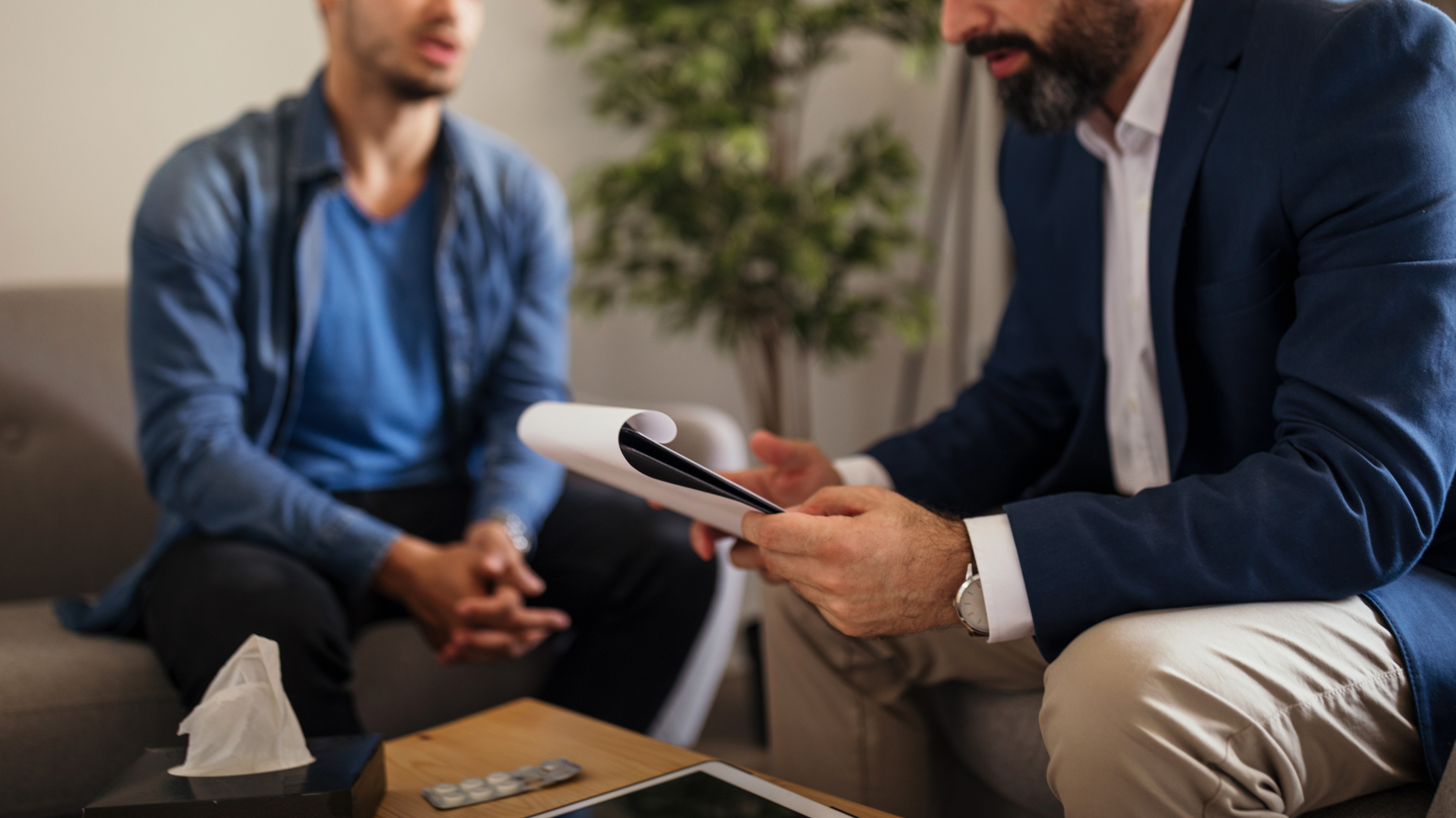 Man consulting with therapist holding a notepad