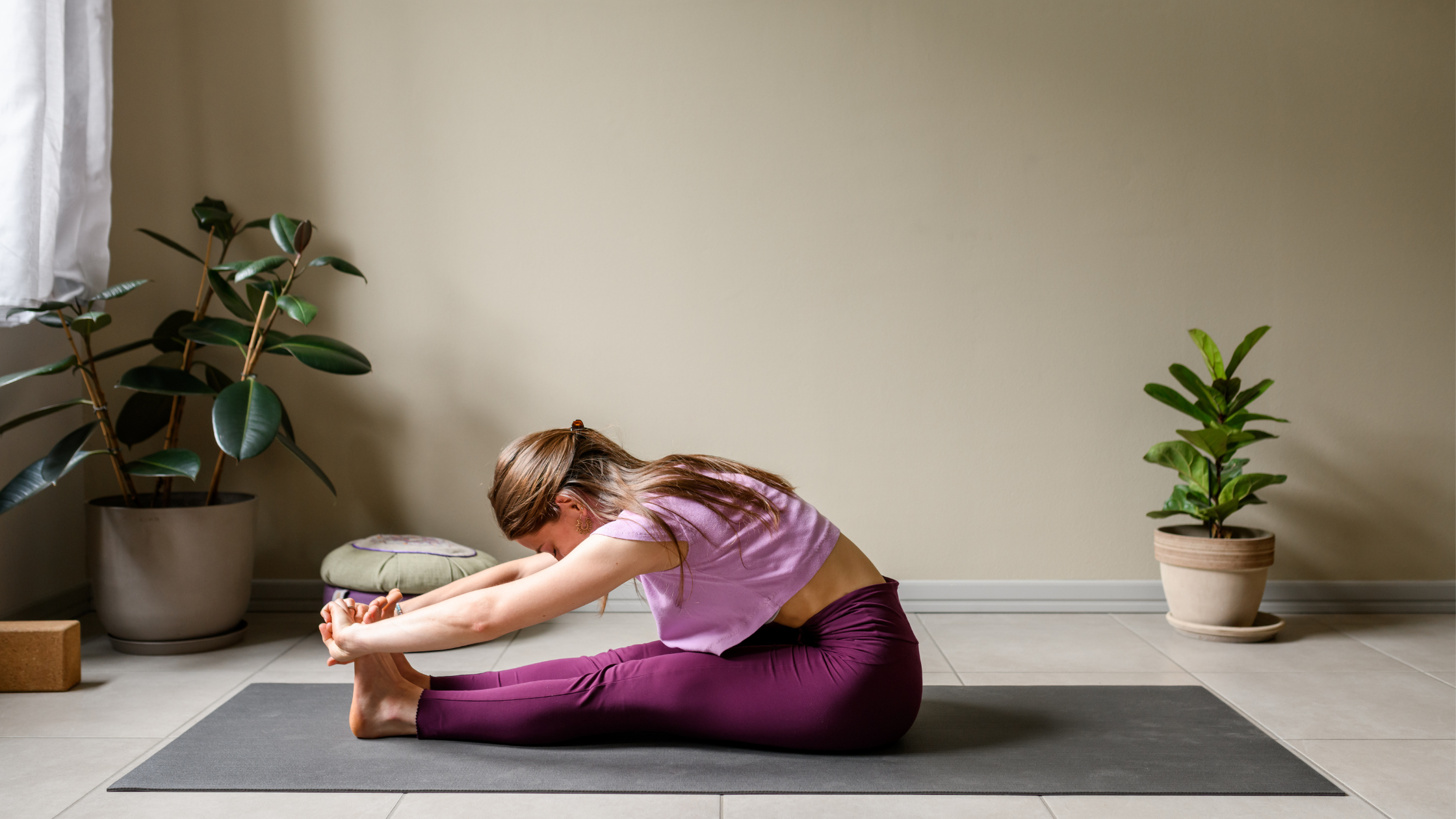Woman stretching forward on yoga mat in calm room