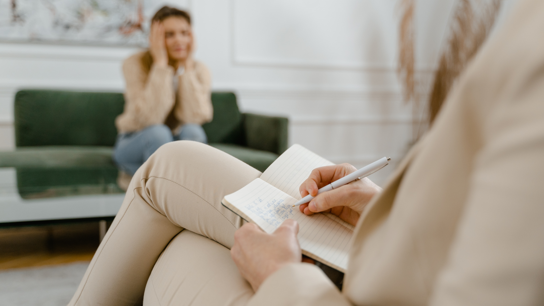 Therapist writing notes with patient sitting on sofa