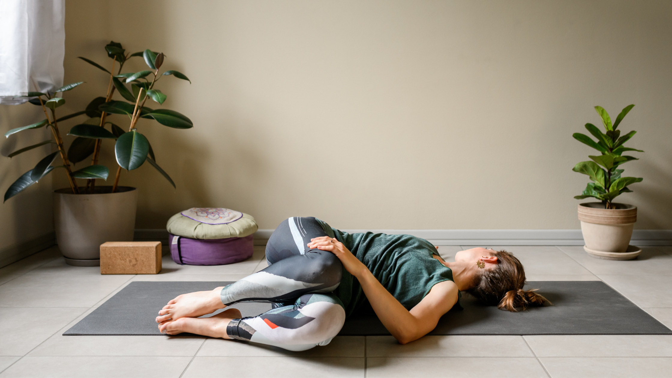 Person lying on side in a reclining yoga twist pose on mat