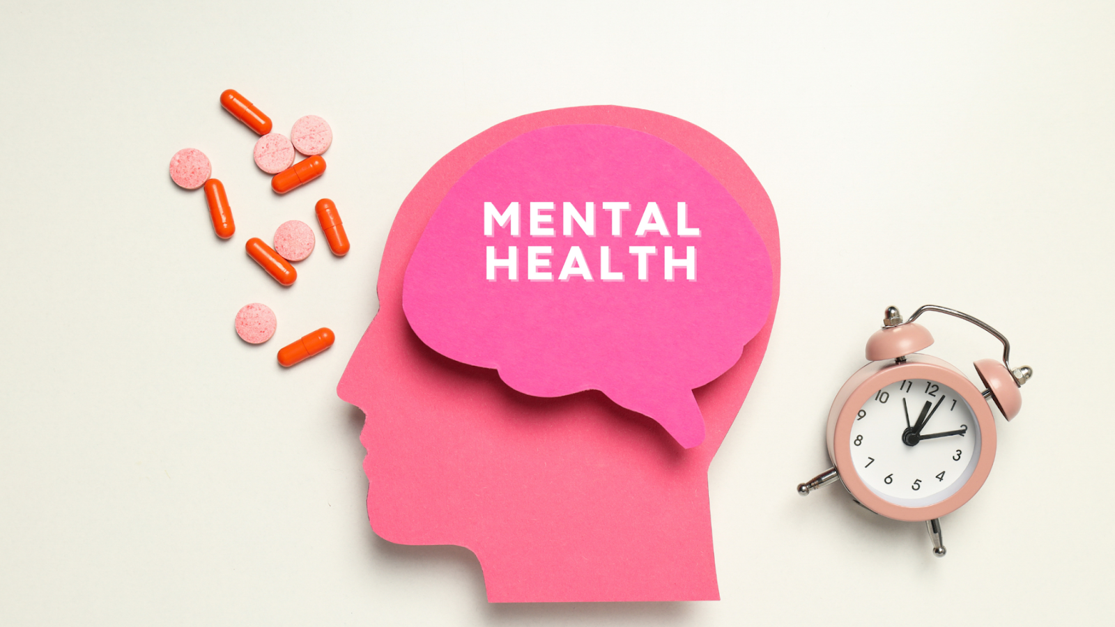 Paper cutout of head with mental health text, pills, and clock