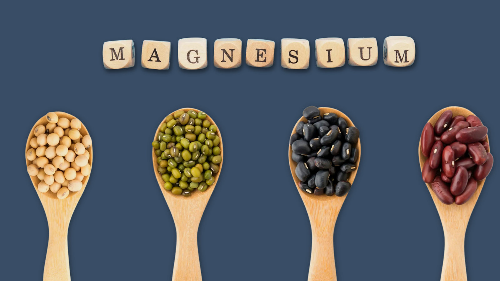 Four wooden spoons with different beans and magnesium spelled in wooden letter blocks