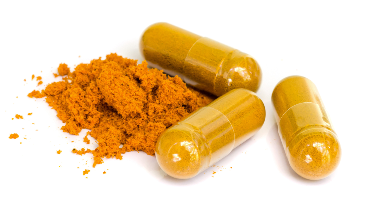 Three turmeric capsules next to turmeric powder on white background