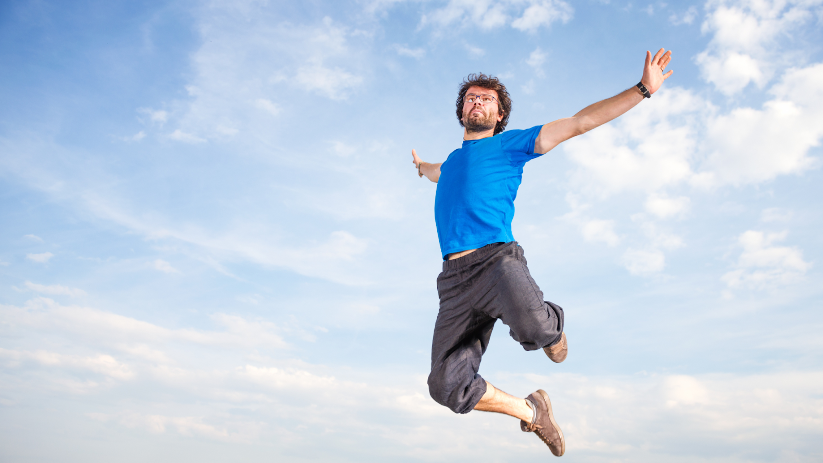 Man jumping energetically against a blue sky