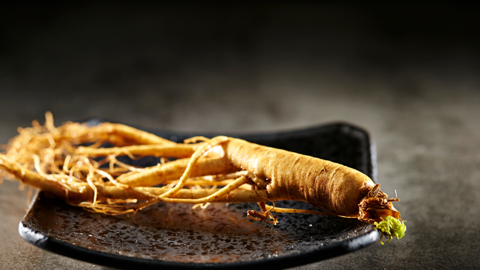 Panax ginseng root on a dark ceramic dish
