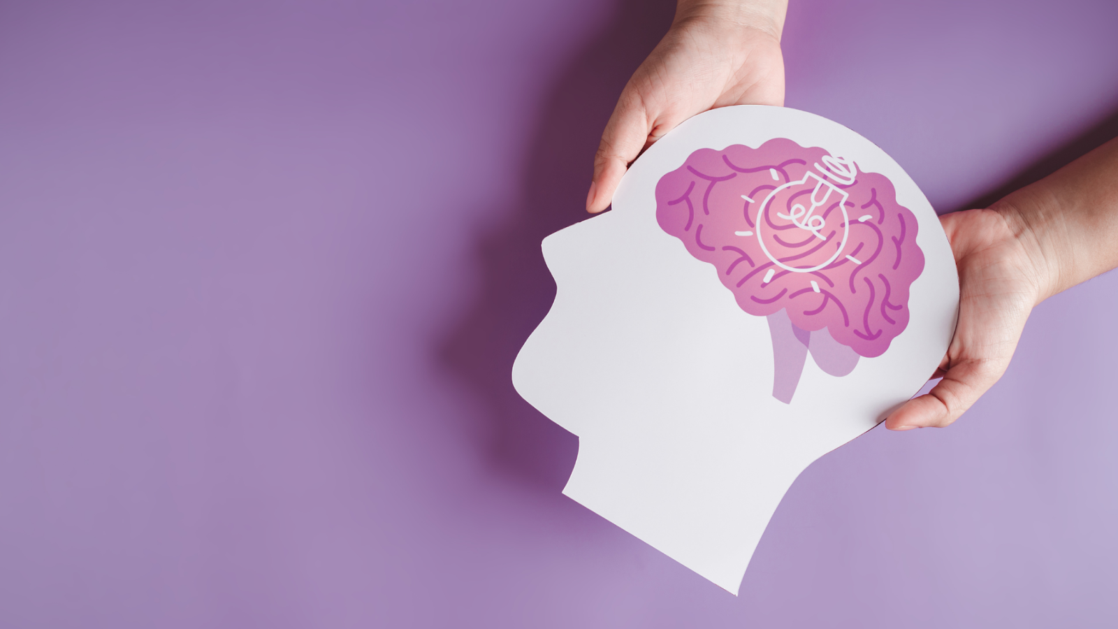 Hands holding paper cutout of head with brain and light bulb illustration