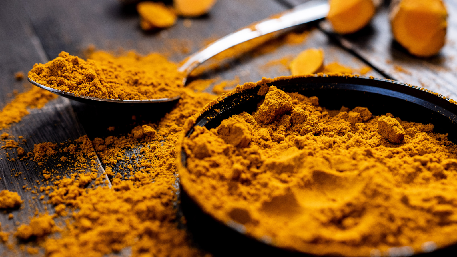 Close-up of turmeric powder with a spoon and black container