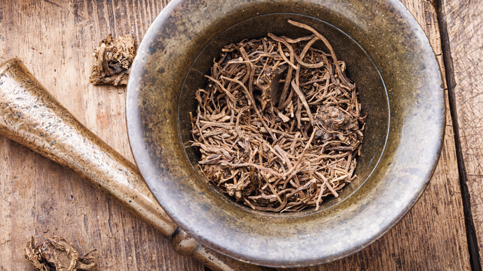 Dried valerian root pieces in a mortar with pestle