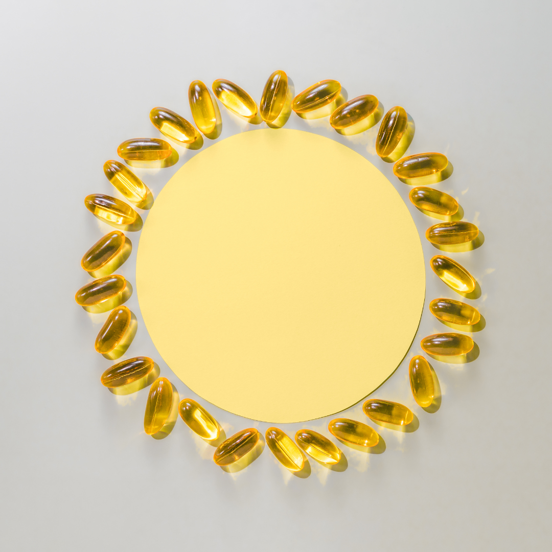 Yellow softgel supplements arranged in a circle on yellow paper