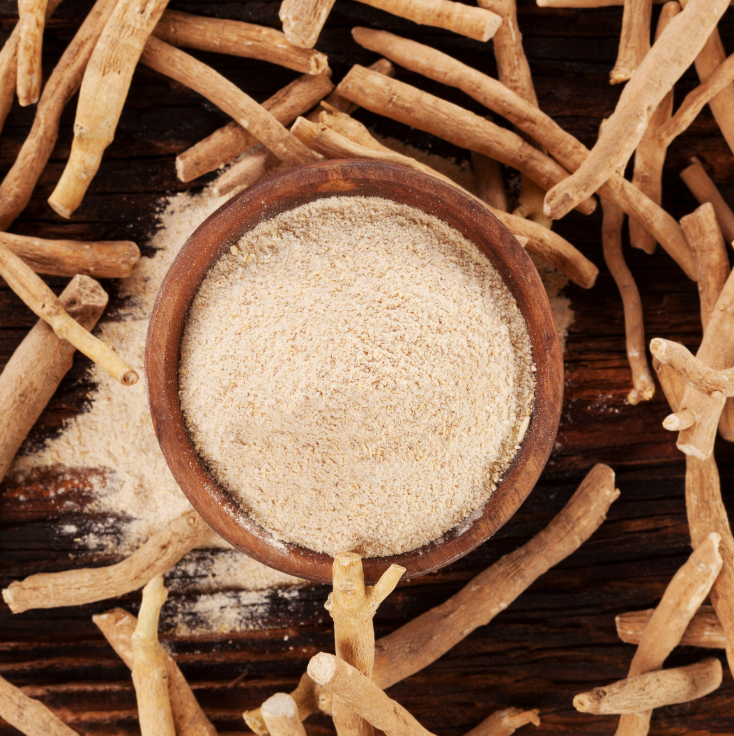 Powdered ashwagandha root in bowl surrounded by dried roots