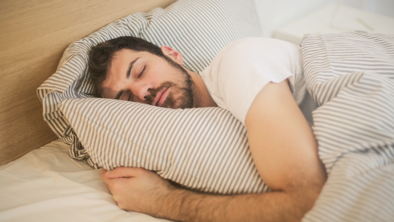 Man sleeping peacefully on striped pillow and blanket