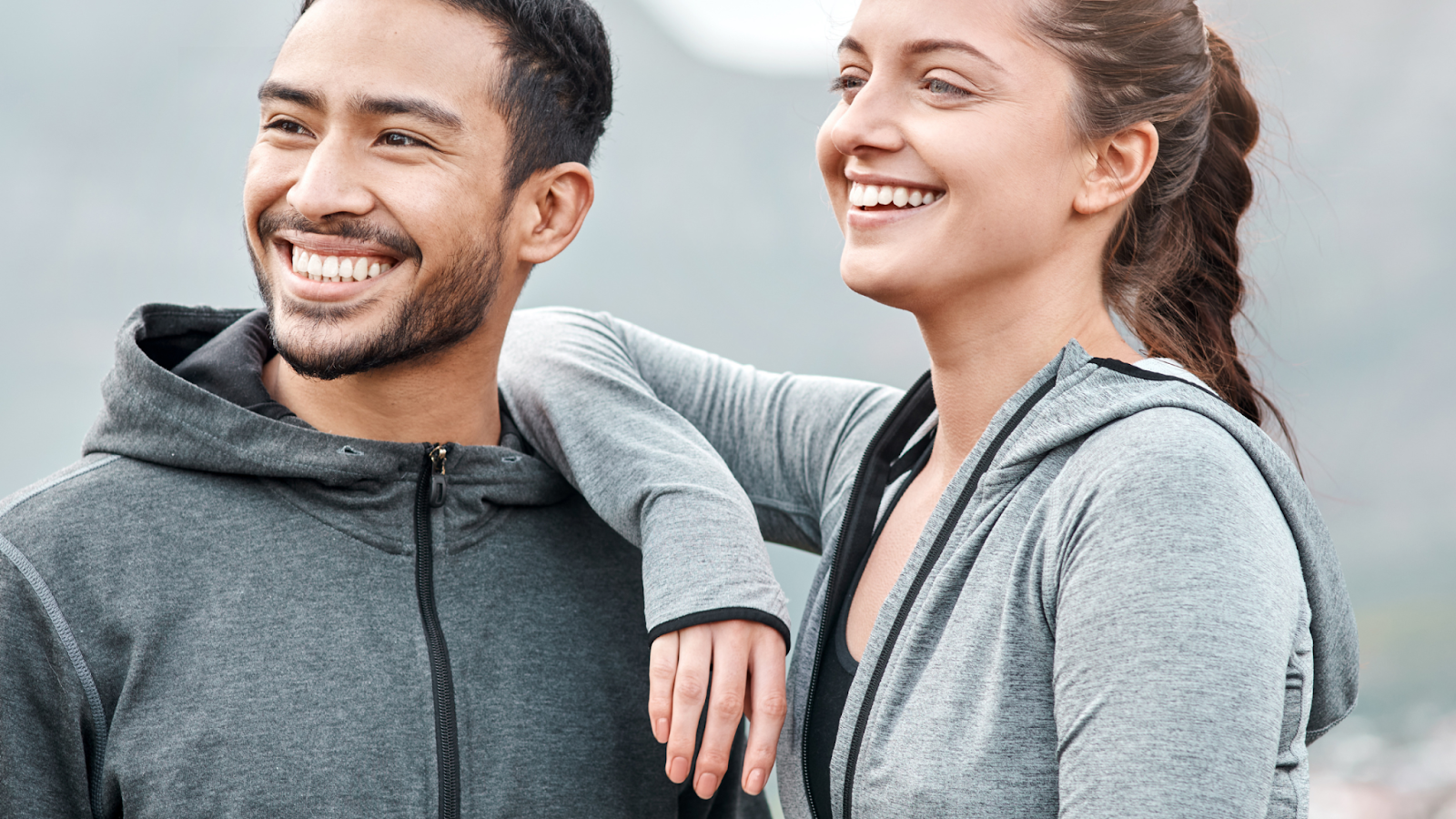 Smiling man and woman in gray athletic wear outdoors