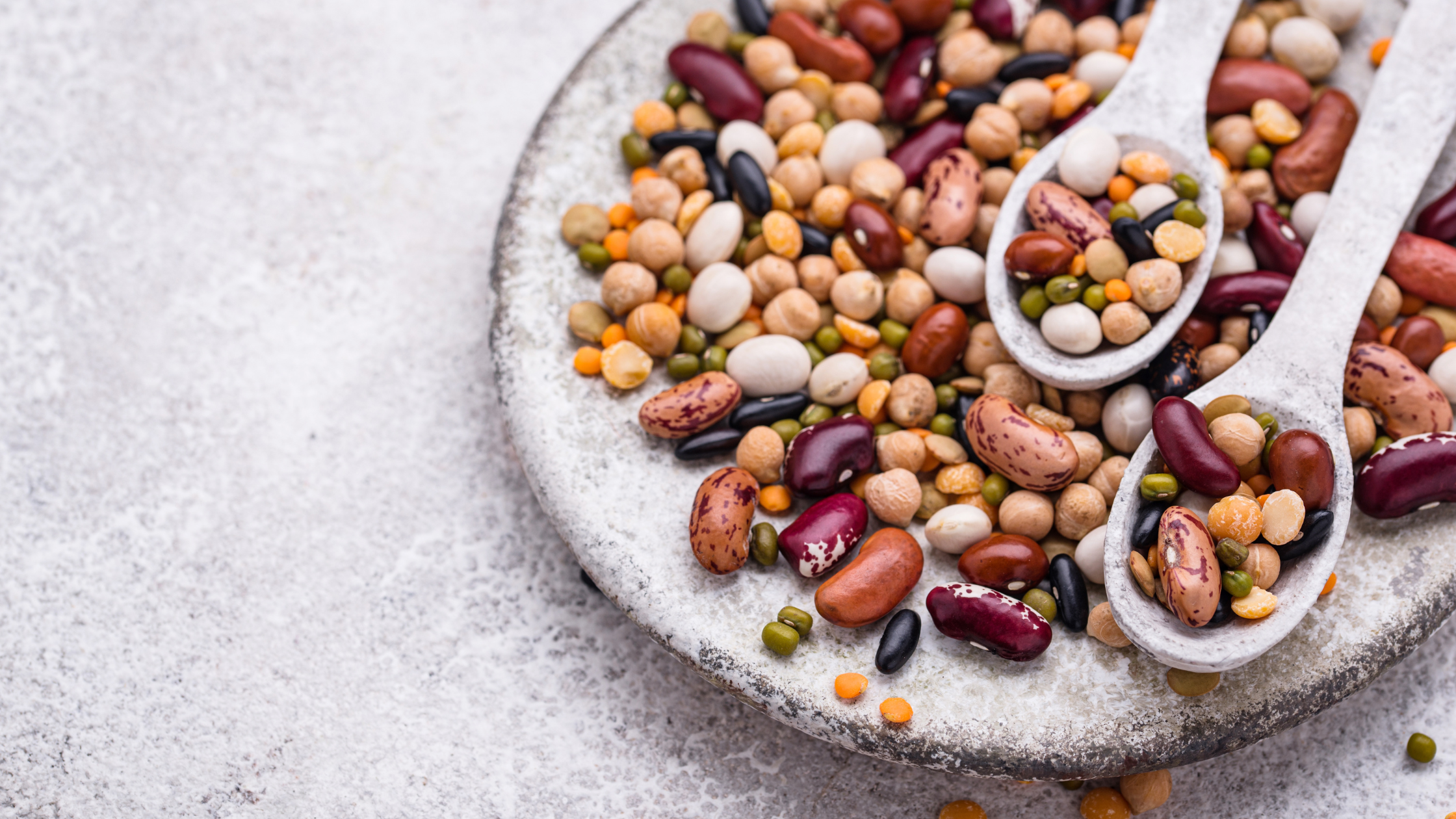 Assorted mixed dry beans and lentils on a plate with spoons