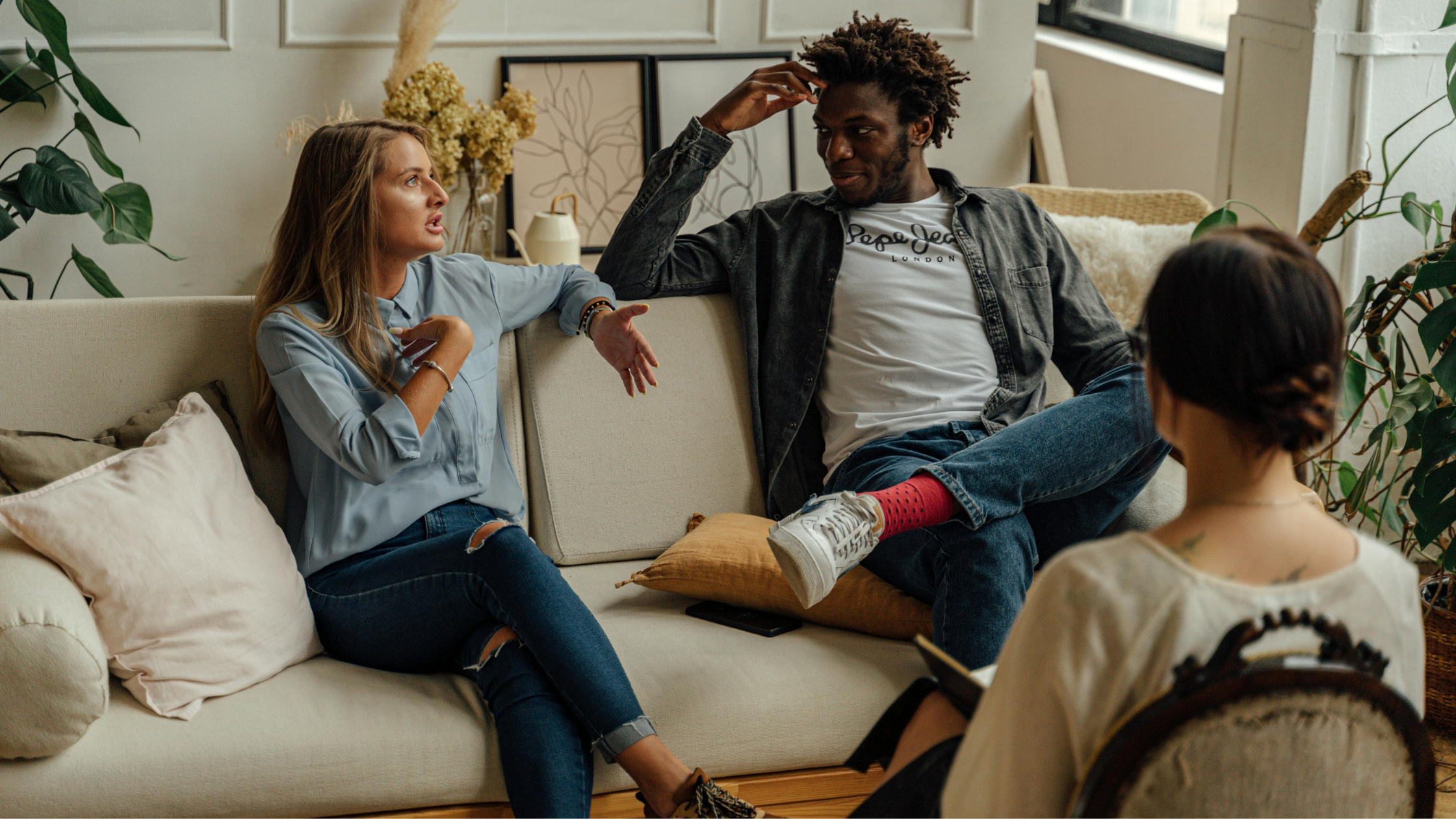 Two people talking during a therapy session with a therapist observing