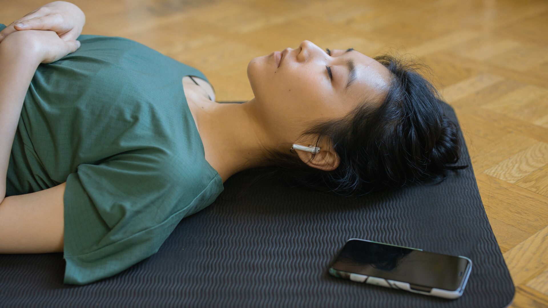 Illustration of a peaceful woman lying on her back in bed, eyes closed and hands resting by her sides, with a soft blue background conveying calm and relaxation. Text overlay reads: "Body Scan Meditation for Sleep — Relax Your Body and Mind."