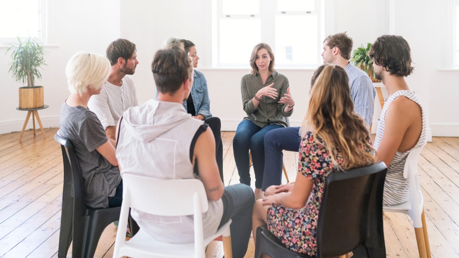 A diverse group of people participating in a free mental health therapy session, guided by a professional counselor in a welcoming community space.