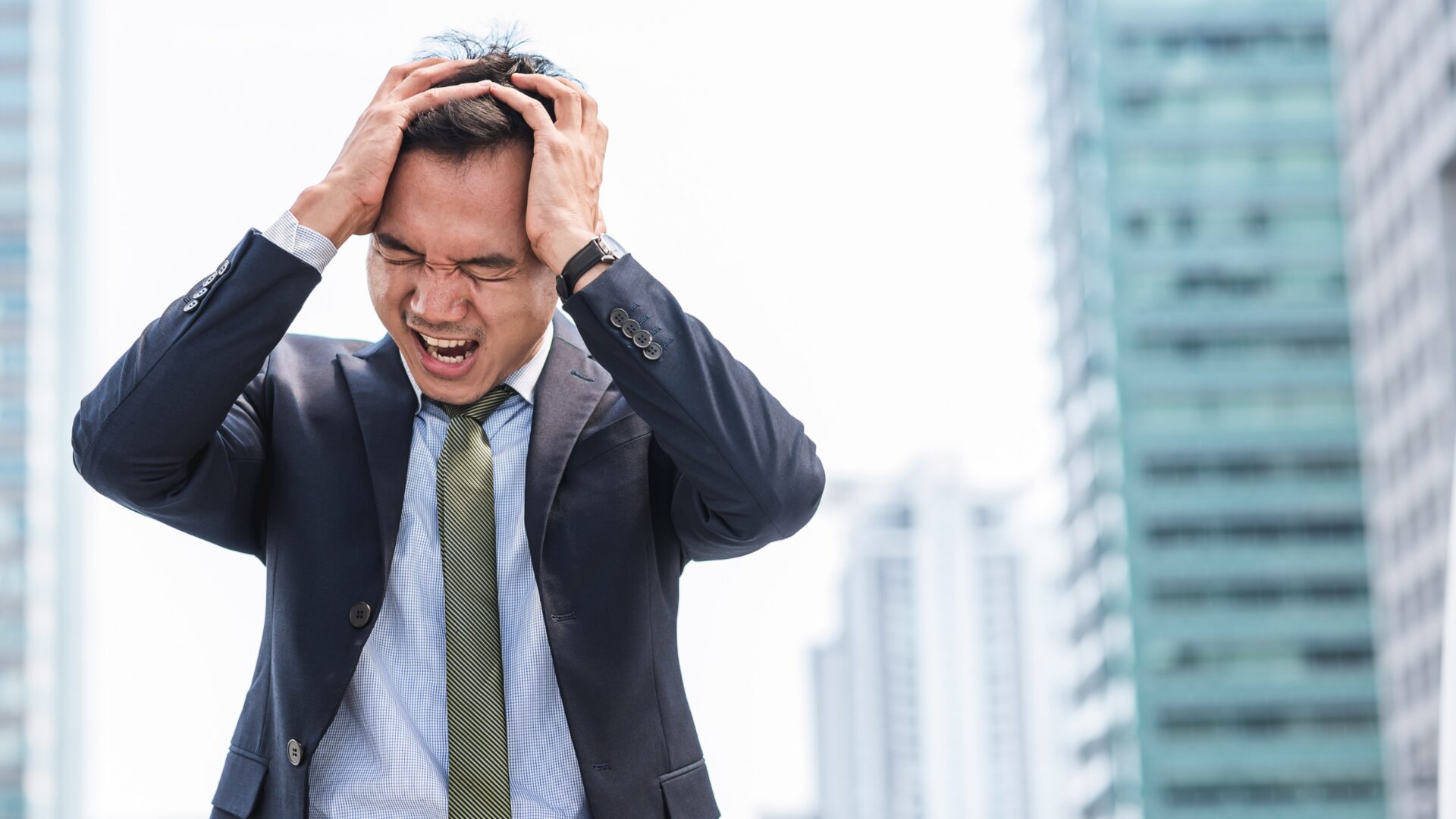 A person sits alone with their head in their hands, surrounded by swirling dark shapes, visually representing mental distress and emotional overwhelm.