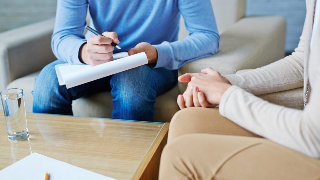A therapist and client sit facing each other in a calm office, engaging in psychodynamic therapy to explore unconscious thoughts and past experiences.