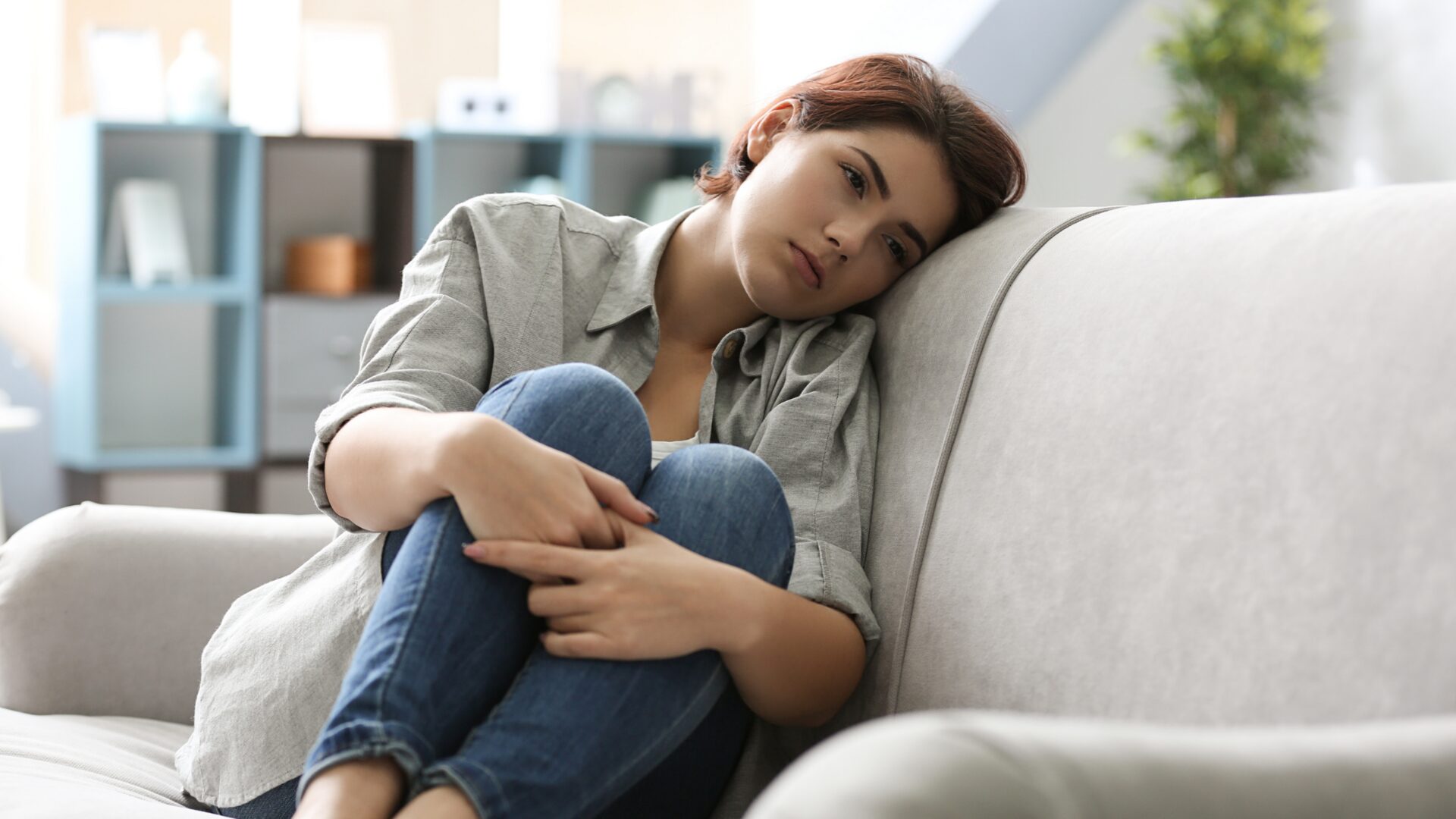 A solitary person sits alone on a park bench, gazing into the distance, symbolizing social isolation and feelings of loneliness in a public space.