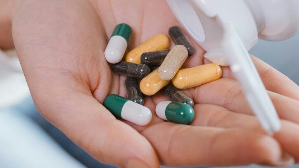 Various memory-boosting supplements including omega-3 capsules, ginkgo biloba tablets, and vitamin B complex displayed on a wooden table.
