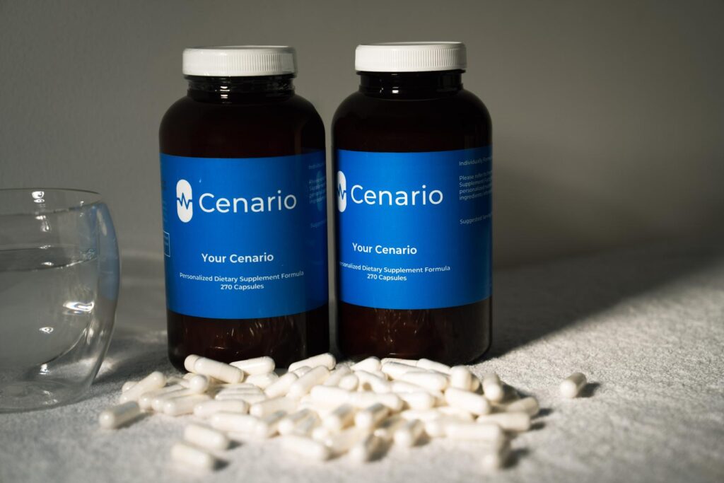 A hand holds a small black coffee cup filled with latte, showcasing heart-shaped latte art. The background is softly blurred, emphasizing the cup and latte design.