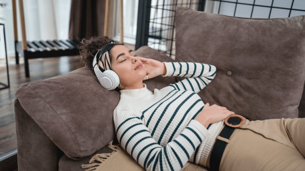 A person lies peacefully in bed at night, eyes closed, listening to a guided meditation for sleep and anxiety, surrounded by a calm, soothing atmosphere.