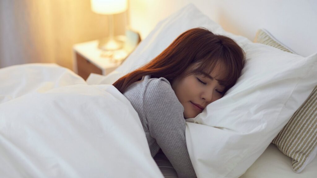 Person adjusting alarm clock and closing curtains at night, illustrating steps to fix a disrupted sleep schedule for better rest and healthier routines.