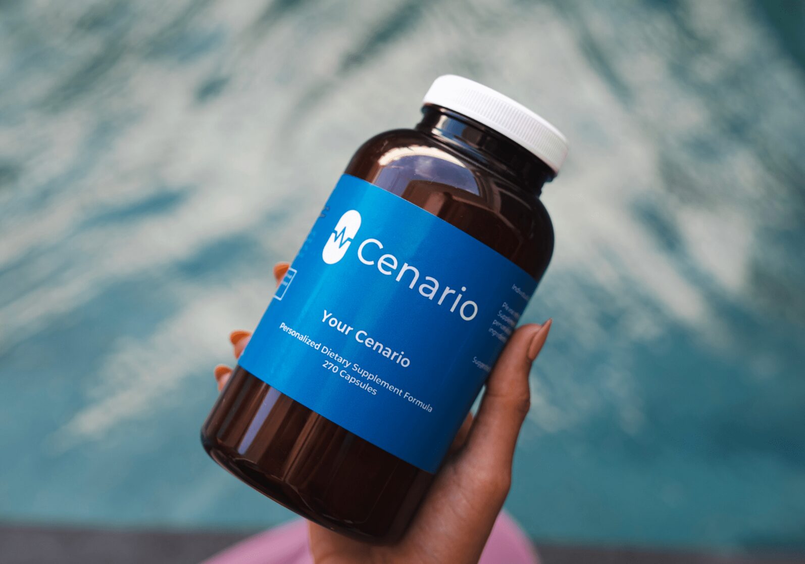 A man in a cream shirt and glasses smiles at the camera, standing in a warm-lit cafe. Shelves with mugs, jars, and plants line the wall behind him.