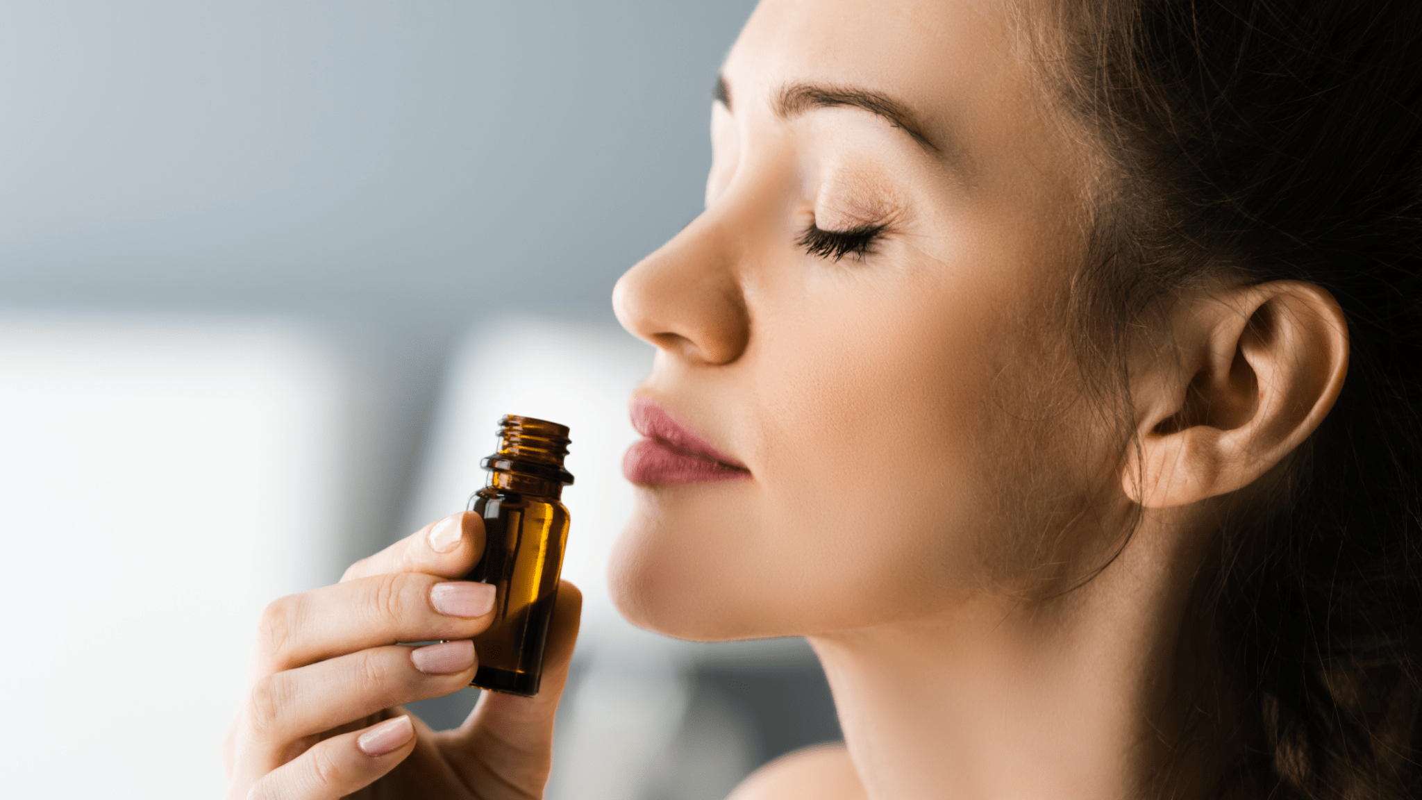 Woman smelling essential oil from small amber bottle