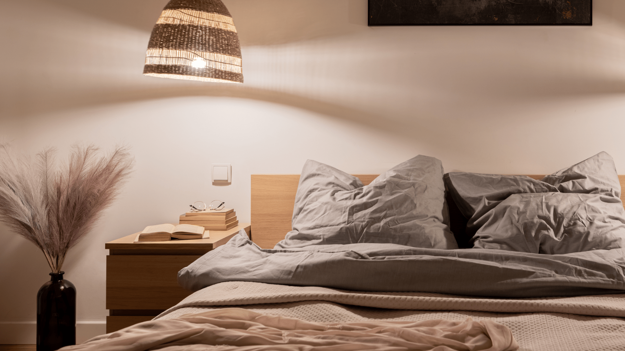 Cozy bed with pillows and side table under warm light