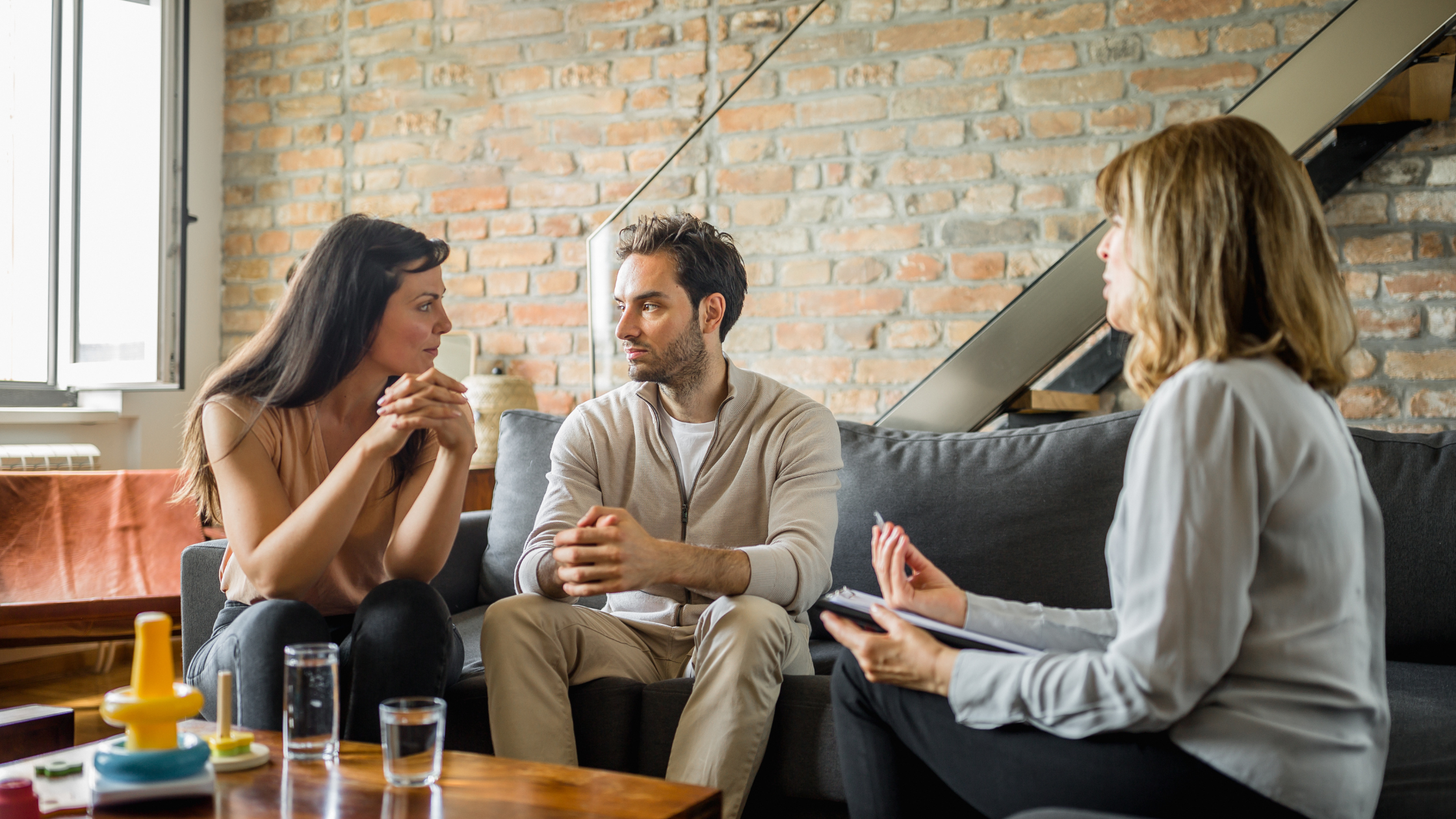 Couple and therapist in a counseling session on sofa