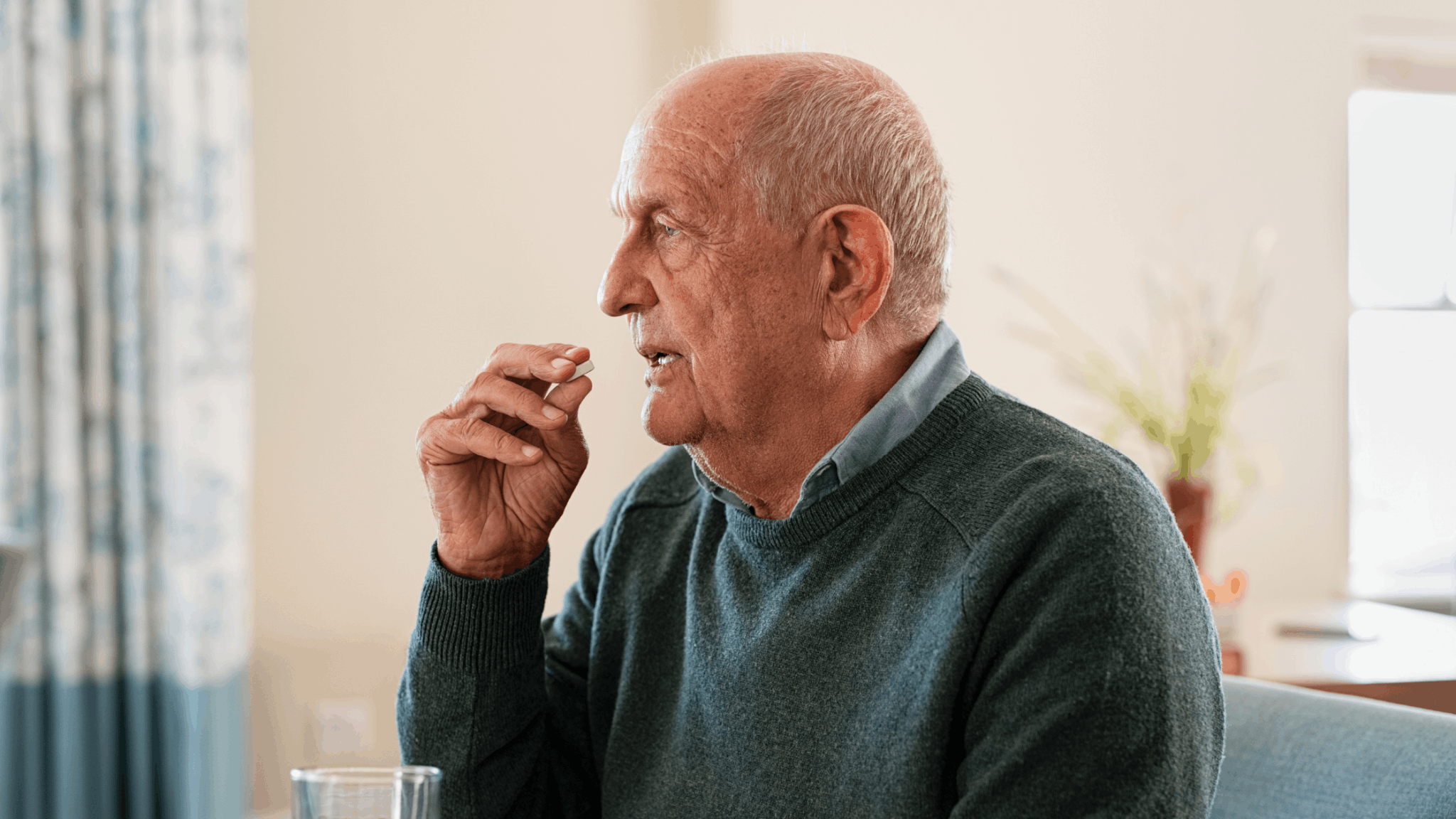 Elderly man about to take a pill indoors