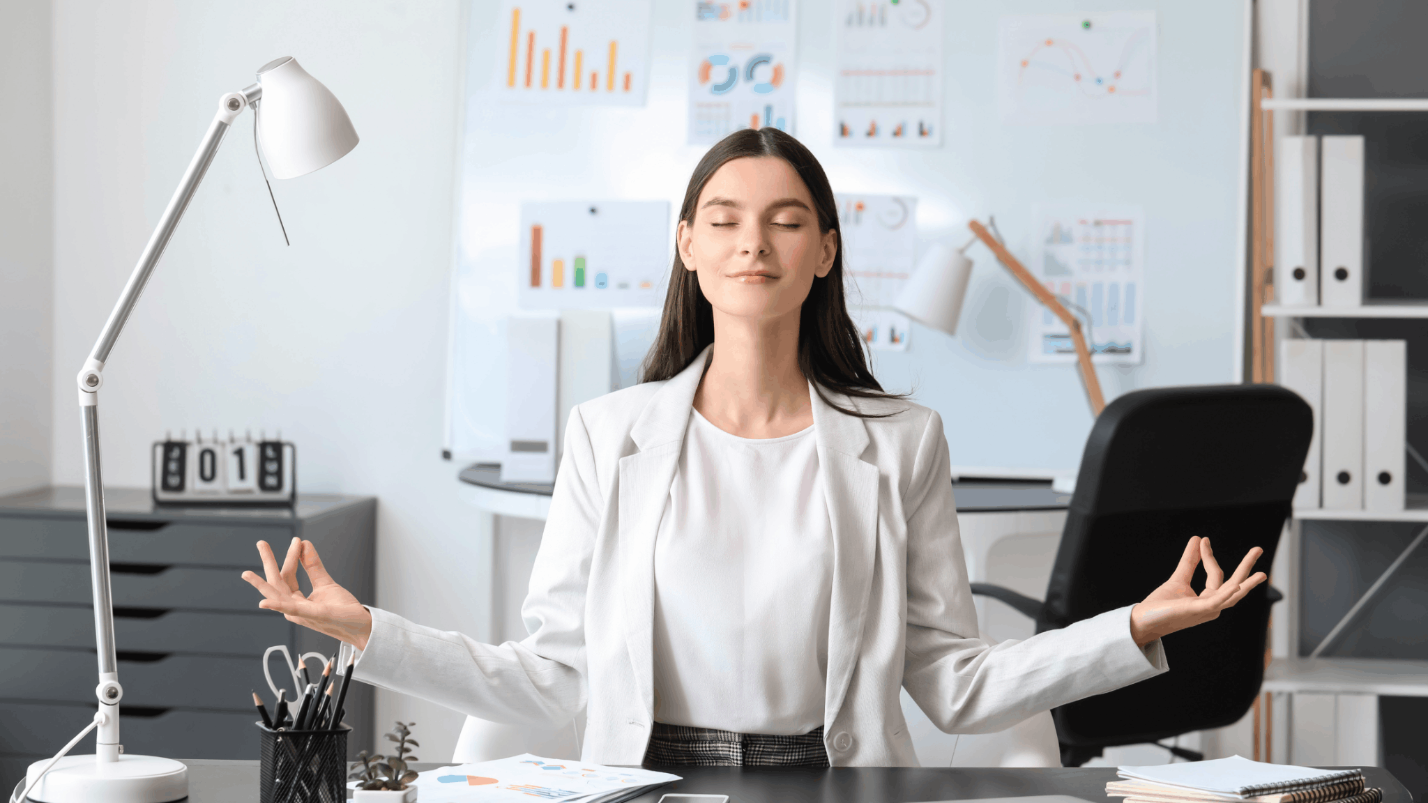 Woman meditating at desk with charts in background