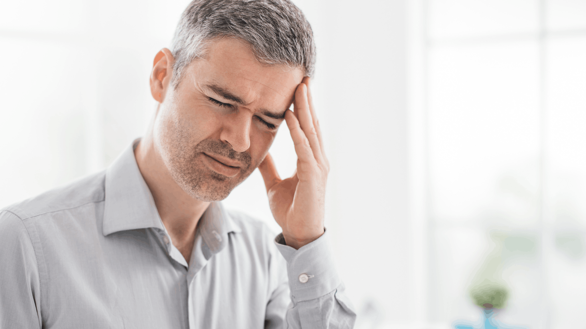 Man with gray hair holding head in pain