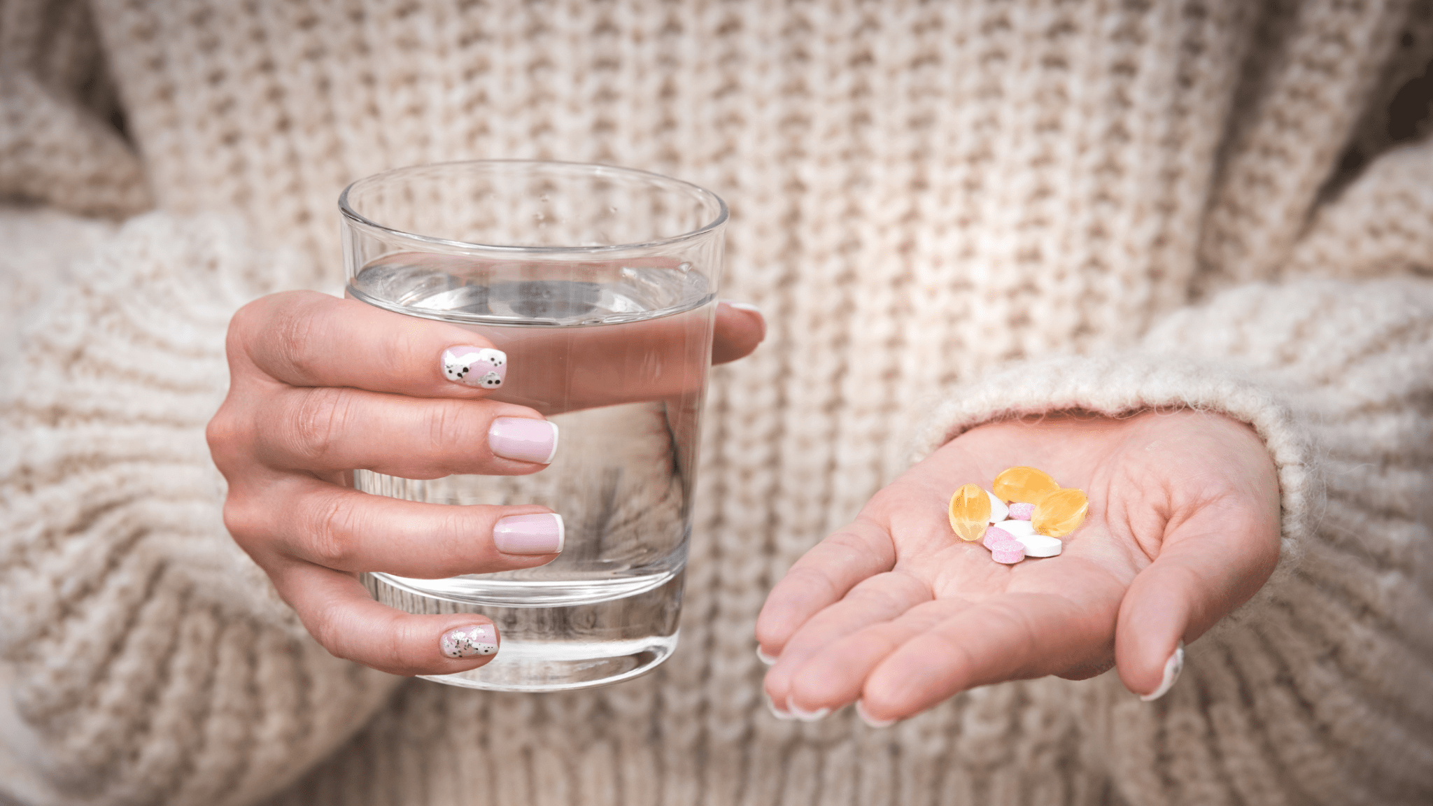 Hand holding various supplements and a glass of water