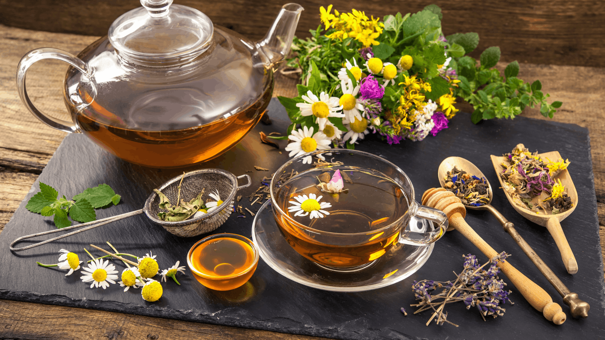 Glass teapot and cup of herbal tea with chamomile flowers and honey