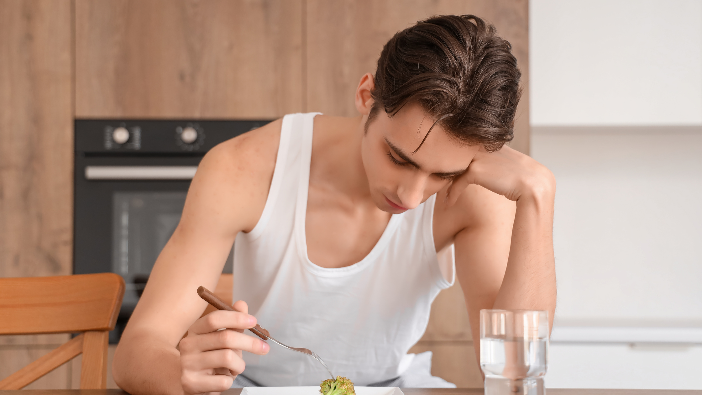 Man looking down at small piece of broccoli on plate