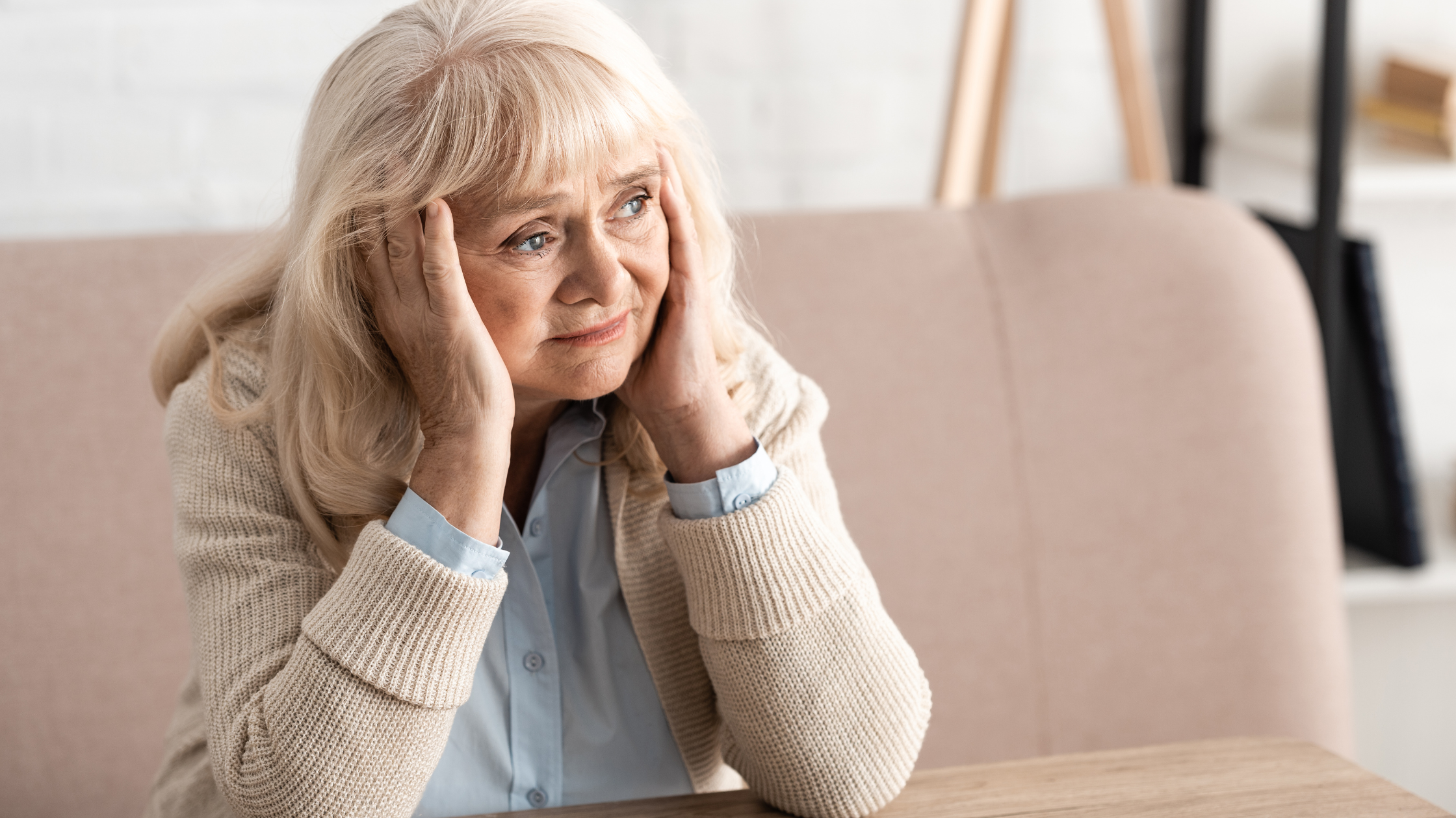 Worried elderly woman sitting with hands on her face